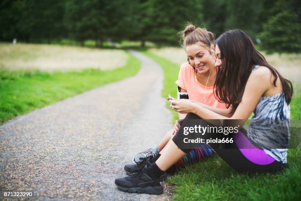 sporty women sharing music on mobile after running - running spikes stock pictures, royalty-free photos & images