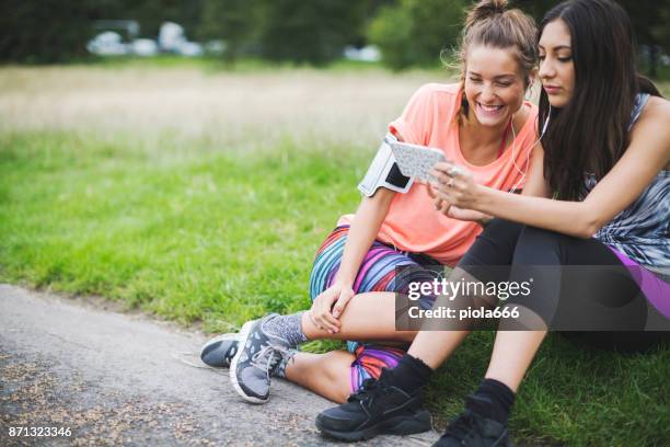 sporty women sharing music on mobile after running - running spikes stock pictures, royalty-free photos & images