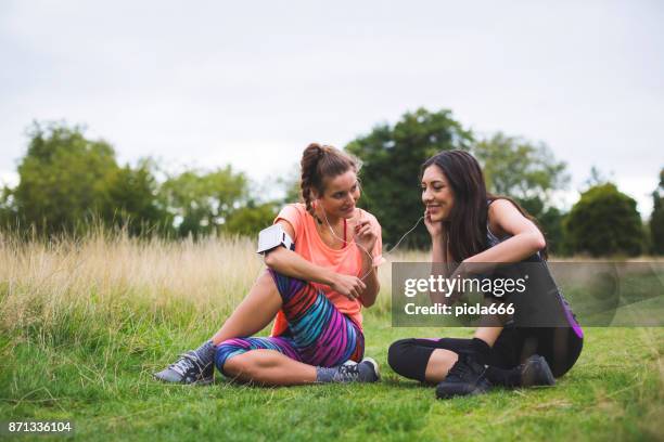sporty women sharing music after running - running spikes stock pictures, royalty-free photos & images