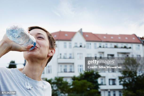 podcasts - woman drinking water from bottle stock-fotos und bilder