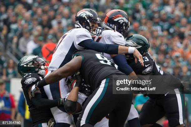 Brock Osweiler of the Denver Broncos throws a pass against Malcolm Jenkins and Fletcher Cox of the Philadelphia Eagles at Lincoln Financial Field on...