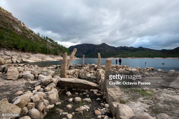 Couple of tourist in Vilarinho das Furnas with the low water level on November 7, 2017 in Terras de Bouro, Portugal. In 1972 the 2000 year old...