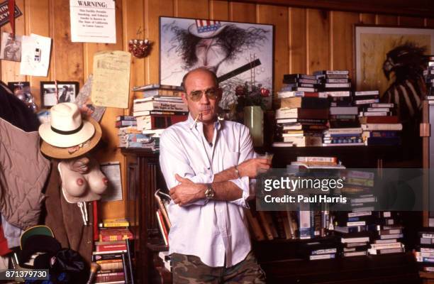 Hunter Thompson aka Hunter S Thompson aka Gonzo Journalist at his ranch standing against a bookcase with a Ralph Steadman picture on the wall on...