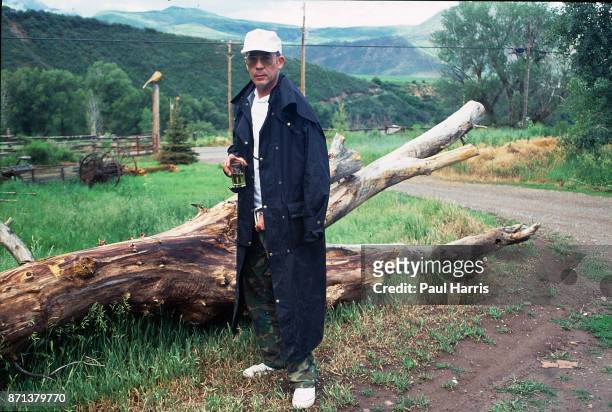 Hunter Thompson aka Hunter S Thompson aka Gonzo Journalist at his ranch standing next to a fallen tree whilst drinking a whisky and smoking on...