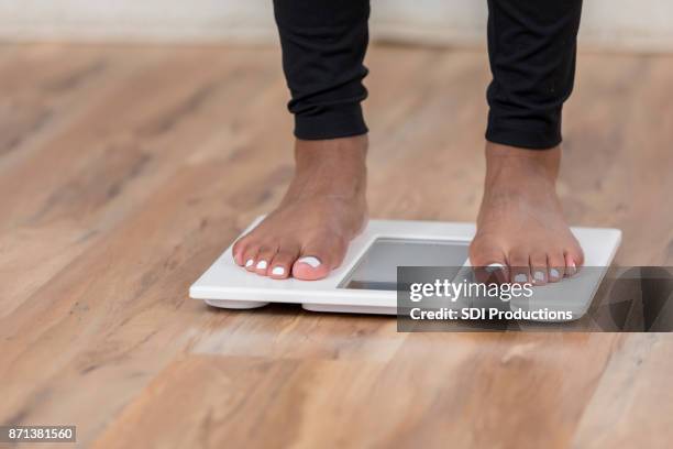 una mujer irreconocible está parado sobre una báscula de baño - skinny black woman fotografías e imágenes de stock