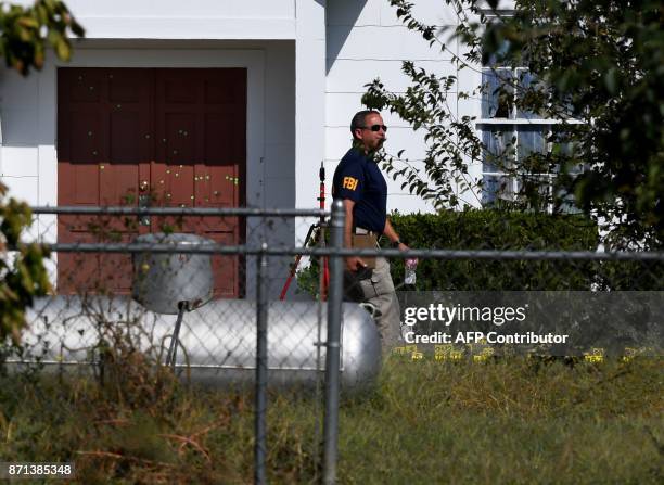 An FBI agent walks past the bullet riddled main door of the First Baptist Church, after a mass shooting that killed 26 people in Sutherland Springs,...