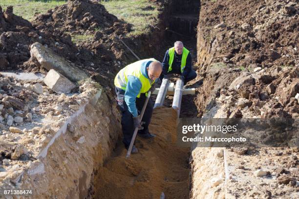 arbeitnehmer arbeitet mit schaufel in einem graben auf pipeline-baustelle - excavation stock-fotos und bilder