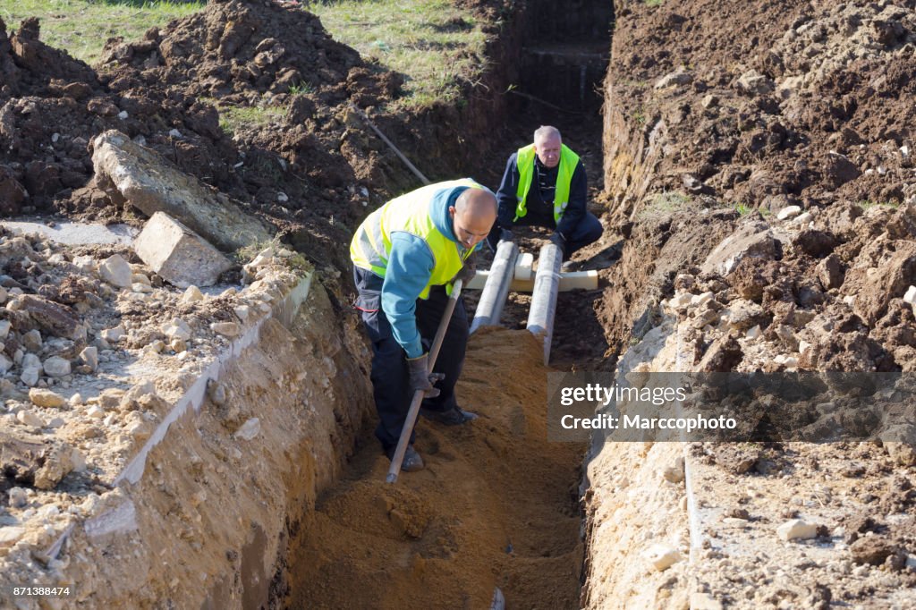 Werknemer werkt met schop in een greppel op de bouwplaats pijpleiding
