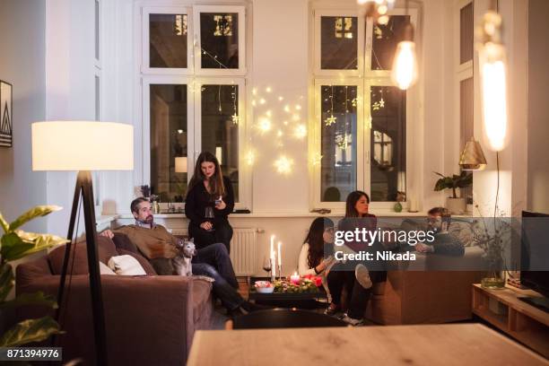 freunde sprechen beim sitzen im wohnzimmer während der weihnachtsfeier - friends talking living room stock-fotos und bilder