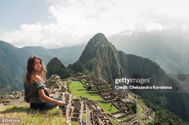 young woman on the cliff in the ancient city of machu picchu, peru. - peru mountains stock-fotos und bilder