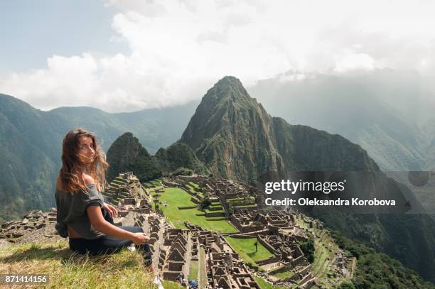 young woman on the cliff in the ancient city of machu picchu, peru. - touring in peru foto e immagini stock