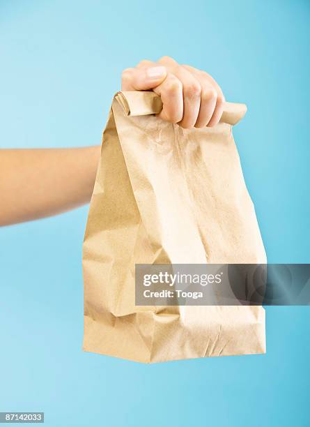 woman holding packed brown bag lunch - taking america to lunch stockfoto's en -beelden