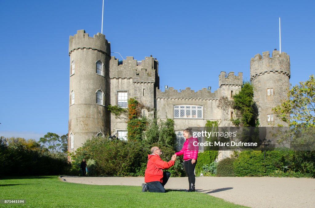 Man vraagt in het huwelijk zijn verloofde voor gevel van de Malahide kasteel in Ierland tijdens dag van de herfst