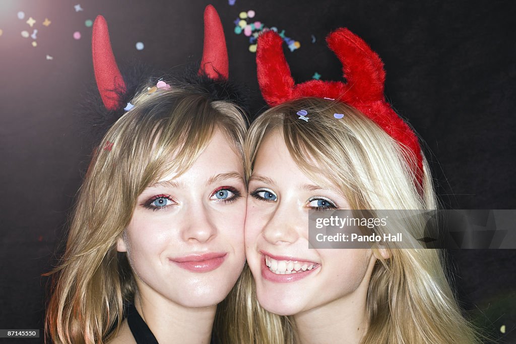 Two Teenage girls wearing devils' horns smiling