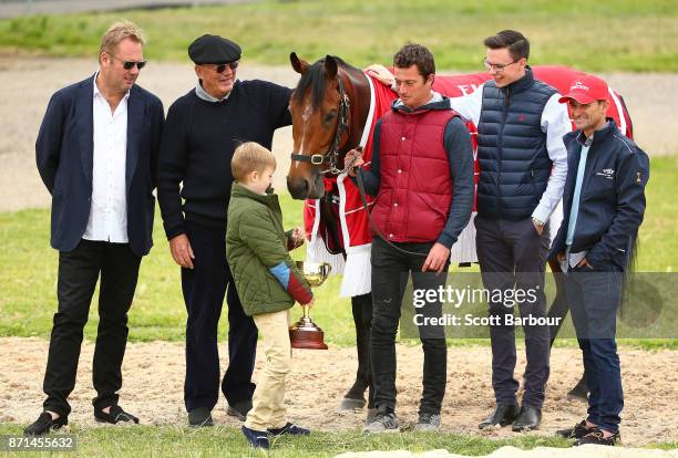 Melbourne Cup winner Rekindling poses with jockey Corey Brown, Nic Williams, Lloyd Williams, Nic Williams' son Frank Williams, strapper MJ Doran and...