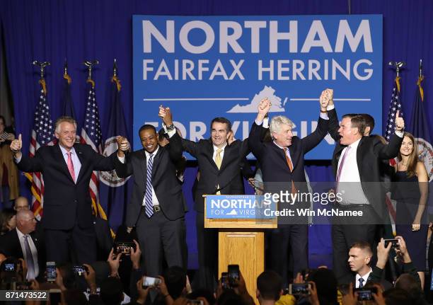 Gov.-elect Ralph Northam links arms with current Gov. Terry McAuliffe, Lt. Gov.-elect Justin Fairfax, Attorney General-elect Mark Herring, and U.S....