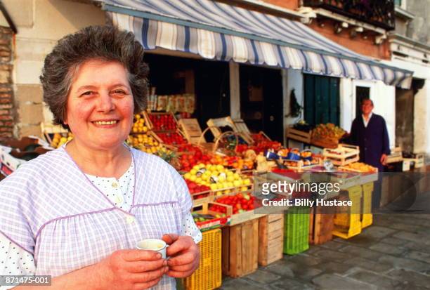 italy, venice, woman outside her fruit and vegetable store - mid adult fotografías e imágenes de stock