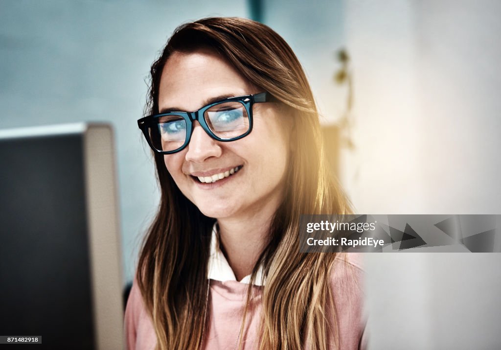 Smiling blonde office worker in glasses is happy at work