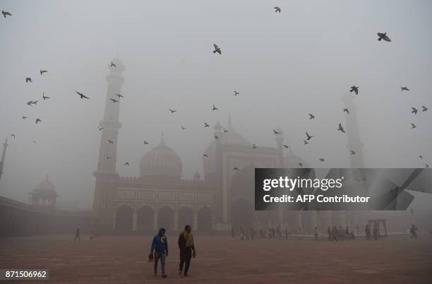 Indian visitors walk through the courtyard of Jama Masjid amid heavy smog in the old quarters of New Delhi on November 8, 2017. Delhi shut all...