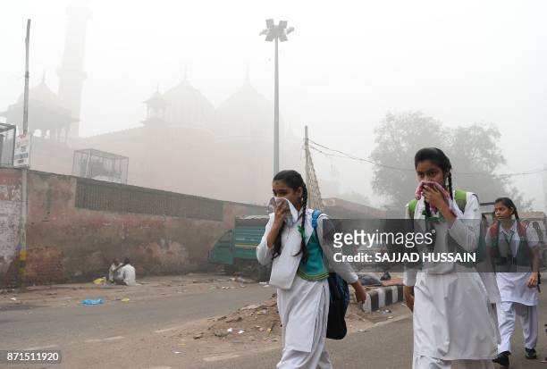 Indian schoolchildren cover their faces as they walk to school amid heavy smog in New Delhi on November 8, 2017. Delhi shut all primary schools on...