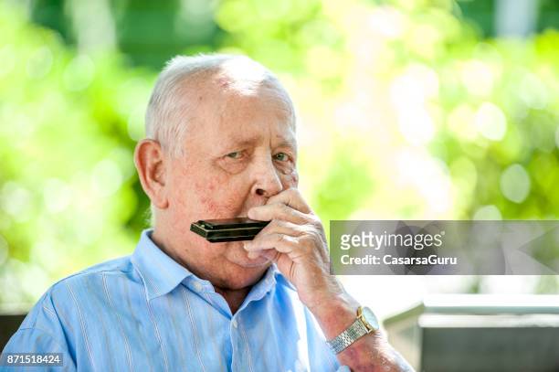 portrait of senior man playing harmonica - harmonica stock pictures, royalty-free photos & images