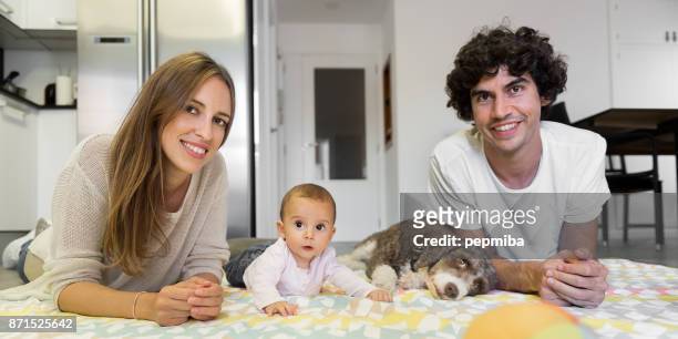 famiglia felice sdraiata con il cane sulla coperta a casa - soltanto un animale foto e immagini stock