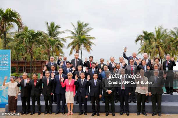 Ministers wave as they pose for the "family photo" after attending the APEC Ministerial Meeting ahead of the Asia-Pacific Economic Cooperation Summit...