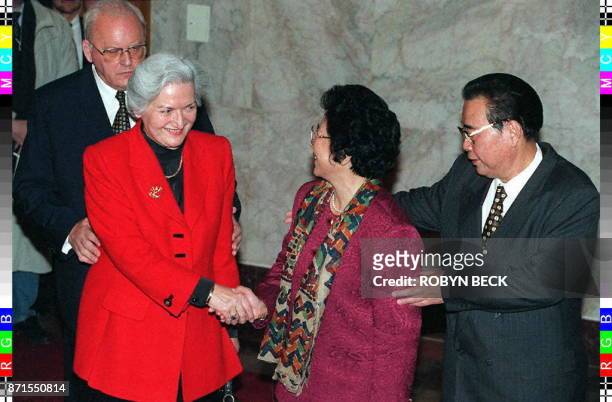 German President Roman Herzog and Chinese Premier Li Peng move their wives, Christiane and Zhu Lin, to the foreground for a handshake as they pose...