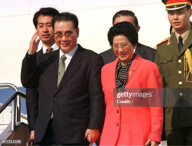 Holding the hand of his wife Zhu Lin, Chinese Prime Minister Li Peng , accompanied by his wife Zhu Lin, reacts to wellwishers upon his arrival at...