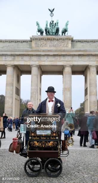 Man poses for a photo with an old music box on the 27th anniversary of the fall of the Berlin Wall at Brandenburg Gate in Berlin, Germany on November...