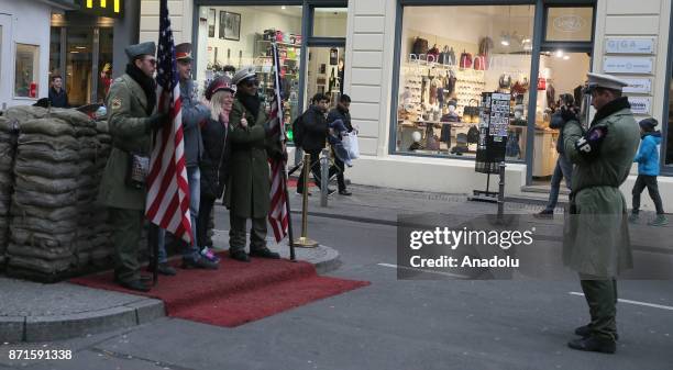 People with soldier uniforms pose for a photo on the 27th anniversary of the fall of the Berlin Wall at Checkpoint Charlie in Berlin, Germany on...