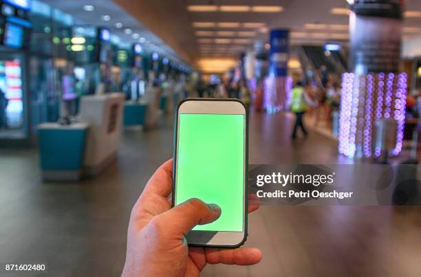 a young man holding a green screen smartphone at cape town international airport. - cape town airport stock pictures, royalty-free photos & images