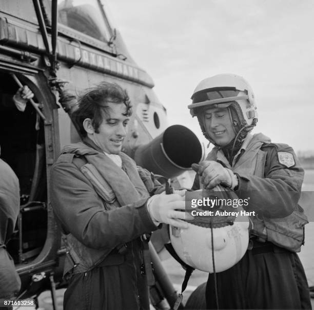 Prince Charles helping a colleague to put on his helmet, during his time with the 845 Naval Air Squadron, 8th January 1975.