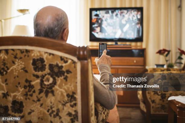 senior man watching tv - man watching tv on couch stockfoto's en -beelden