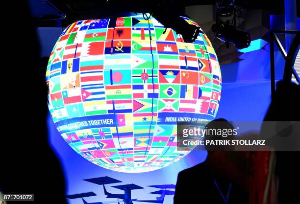 Visitors walk past a sphere featuring flags of countries of the world displayed at the pavillion of India on November 8, 2017 during the COP23 United...