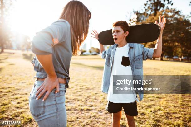 moeder van de zoon met de skateboard dwars - berispen stockfoto's en -beelden