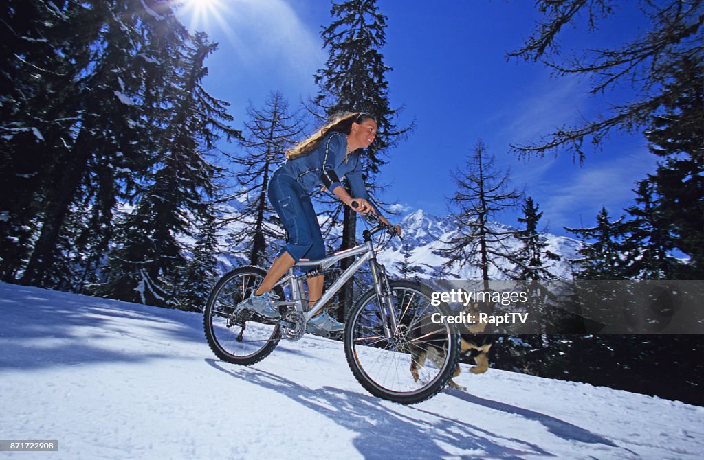 A young lady Riding her Mountain Bike with her pet dog.