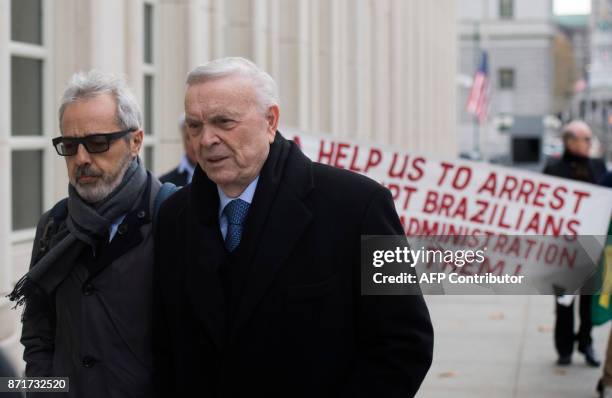 Protesters carry a sign behind former Brazilian National Football Federation president Jose Maria Marin as he arrives on November 8, 2017 at Brooklyn...