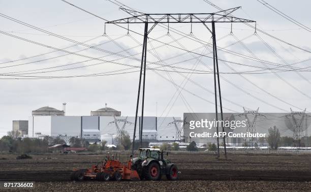 Tractor drives on a field past electricity pylons near the Blayais Nuclear Power Plant operated by French electric company Electricite de France ,...