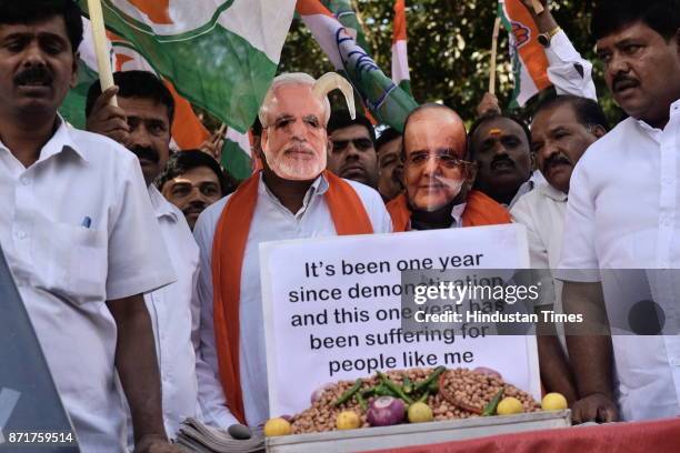 Karnataka Pradesh Congress Committee member sports a caricatured mask of the prime minister of India Narendra Modi and Finance Minister Arun Jaitley...