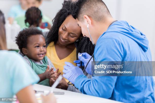 adorable baby boy claps during medical exam - community health stock pictures, royalty-free photos & images