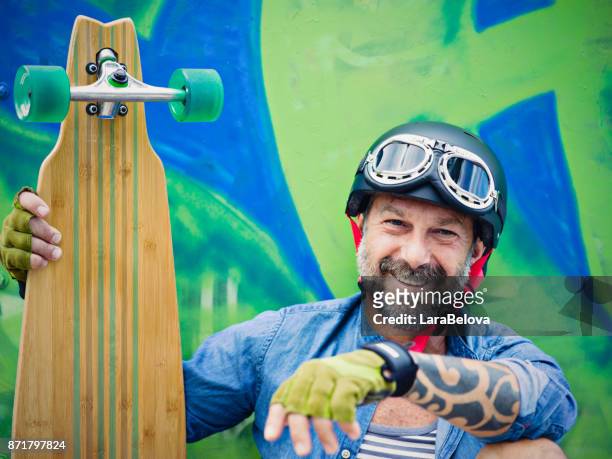 mature man with longboard, graffiti on background - exhilaration stock pictures, royalty-free photos & images