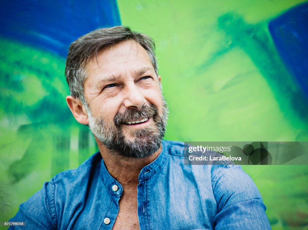 Portrait of mature man, graffiti on background