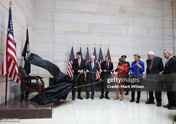 Members of Congress pull a rope to unveil a POW/MIA chair during a ceremony to honor American prisoners of war and the nearly 83,000 servicemen and...