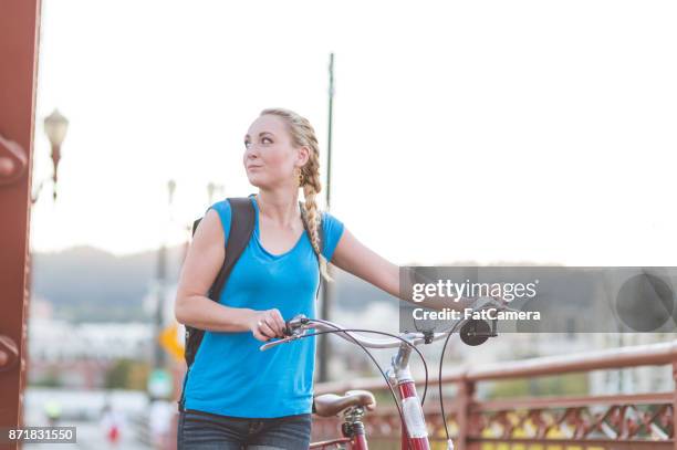 attraktive junge frau geht auf brücke gehweg fahrrad an einem sonnigen nachmittag - ameisenstraße stock-fotos und bilder