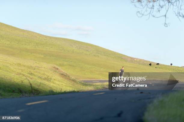 mid adult man longboards down rural highway - i pace concept car stock pictures, royalty-free photos & images