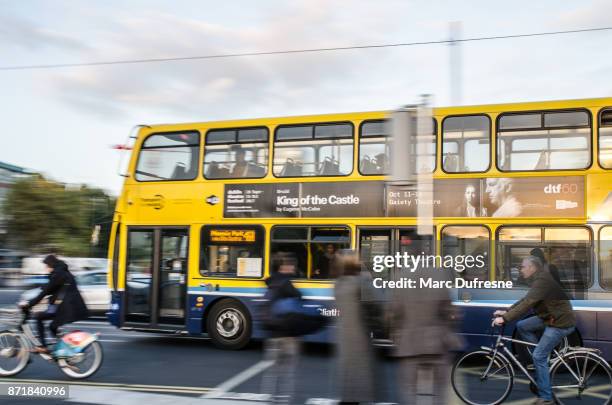 side view of cyclists besides of a double-decker bus in downtown o'connell street of dublin ireland during rush hour a day of autumn - double decker bus stock pictures, royalty-free photos & images