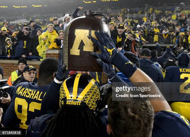 Michigan's Devin Bush carries the Little Brown Jug off the field with his teammates following Michigan's 33-10 win over Minnesota in a college...