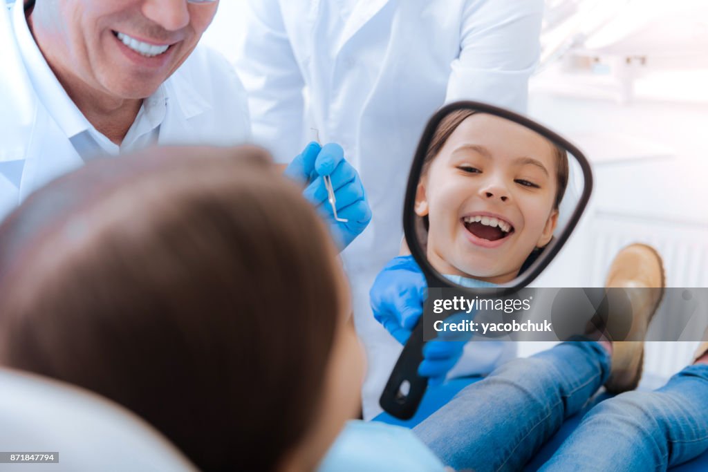 Joyful cute girl looking into the mirror