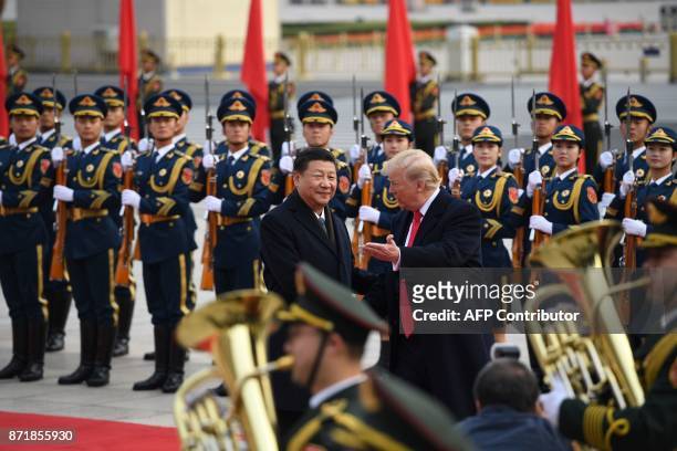 China's President Xi Jinping and US President Donald Trump review Chinese honour guards during a welcome ceremony at the Great Hall of the People in...